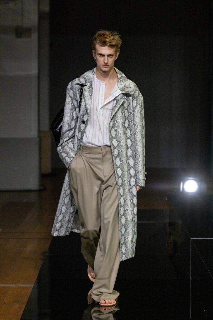 A relaxed gray printed coat paired with beige wide-leg pants and a collared long-sleeve shirt.