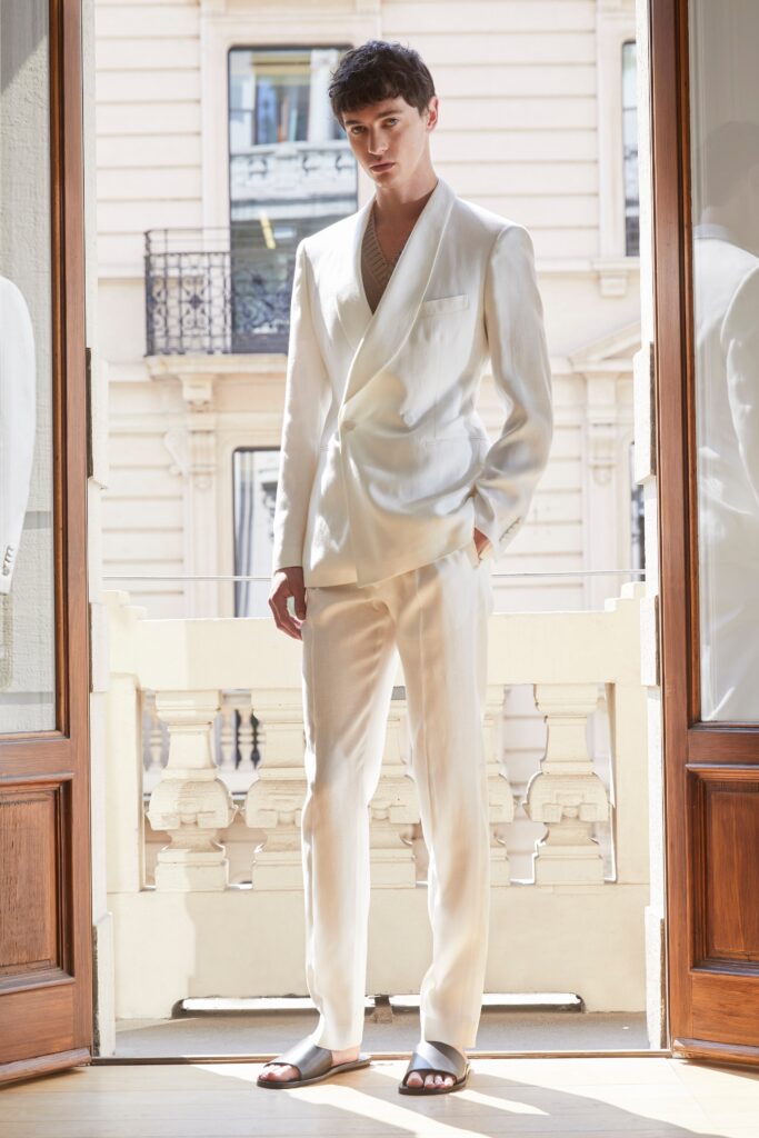 A tailored white suit with long sleeves and a collared design, featuring buttoned details.