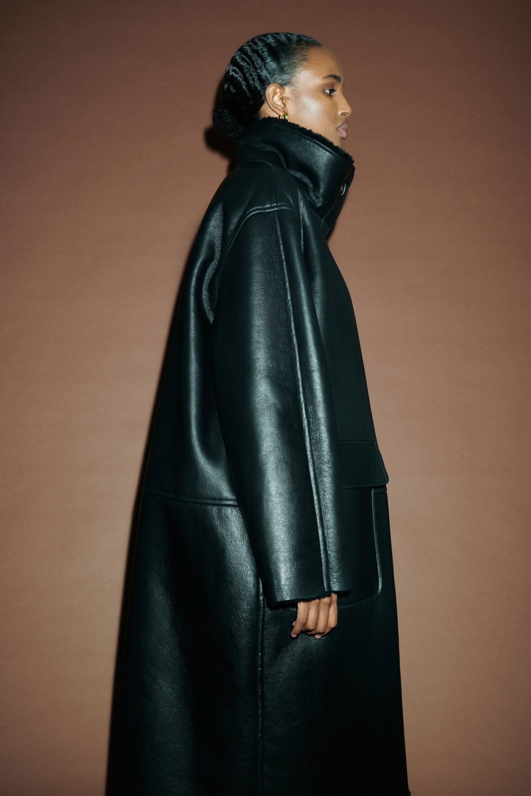 An oversized black leather coat with a high neckline and structured design.