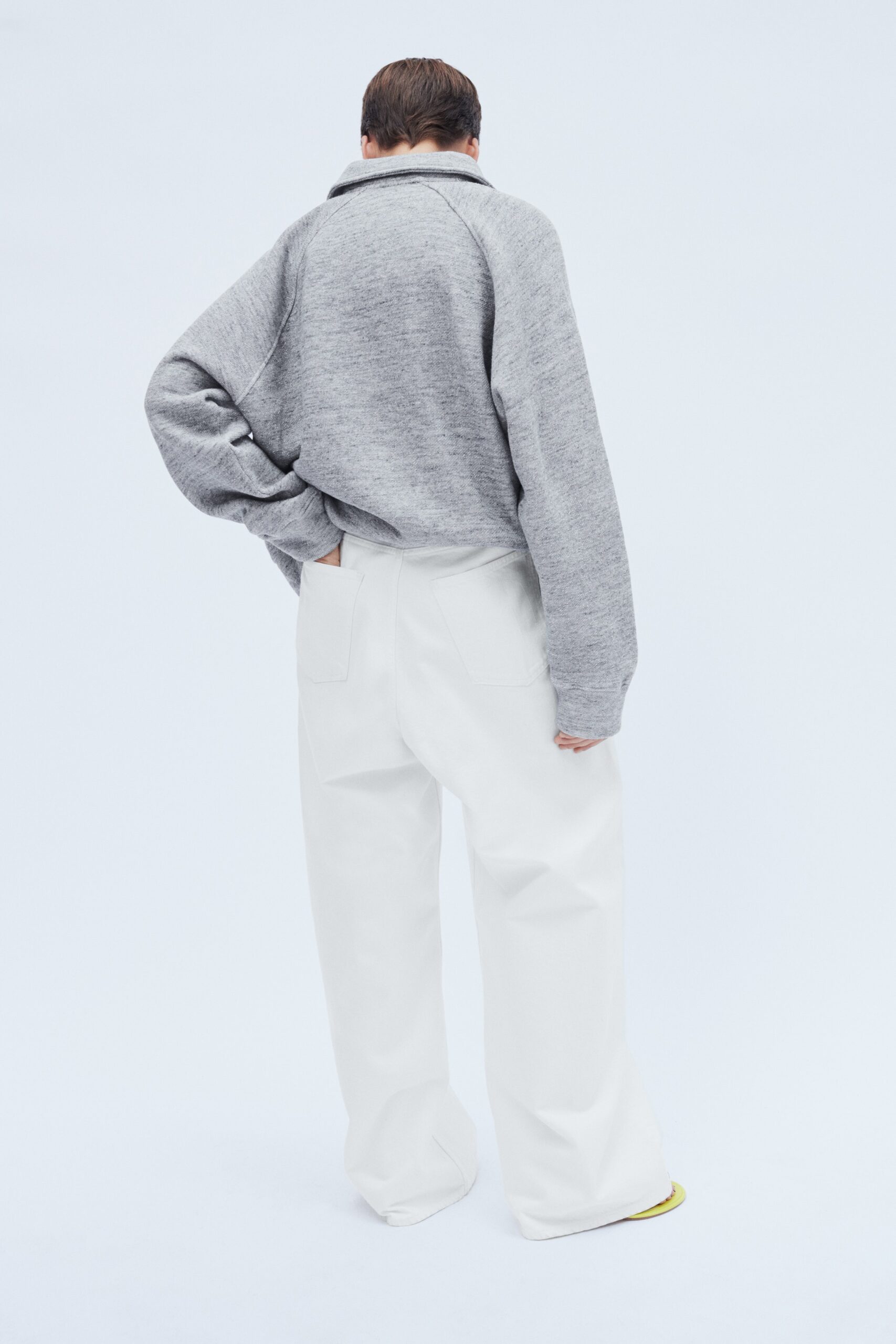 An oversized gray long-sleeve sweater with a collar paired with straight-leg white pants.