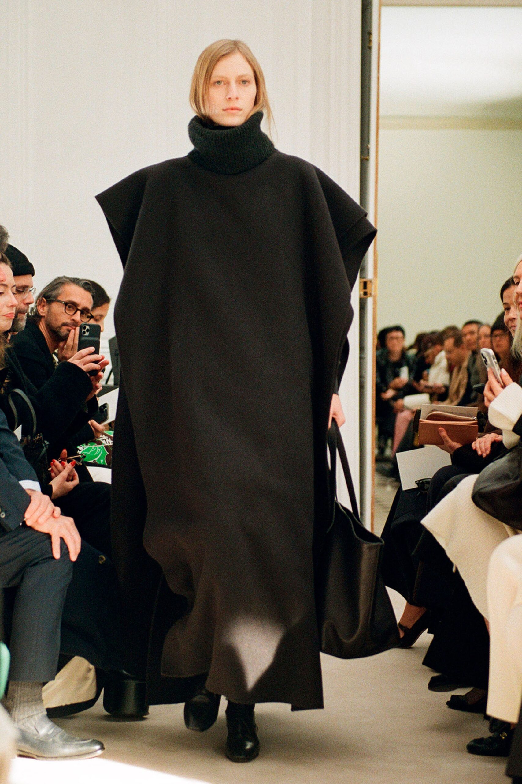 An oversized black wool poncho with a turtleneck and asymmetric design.