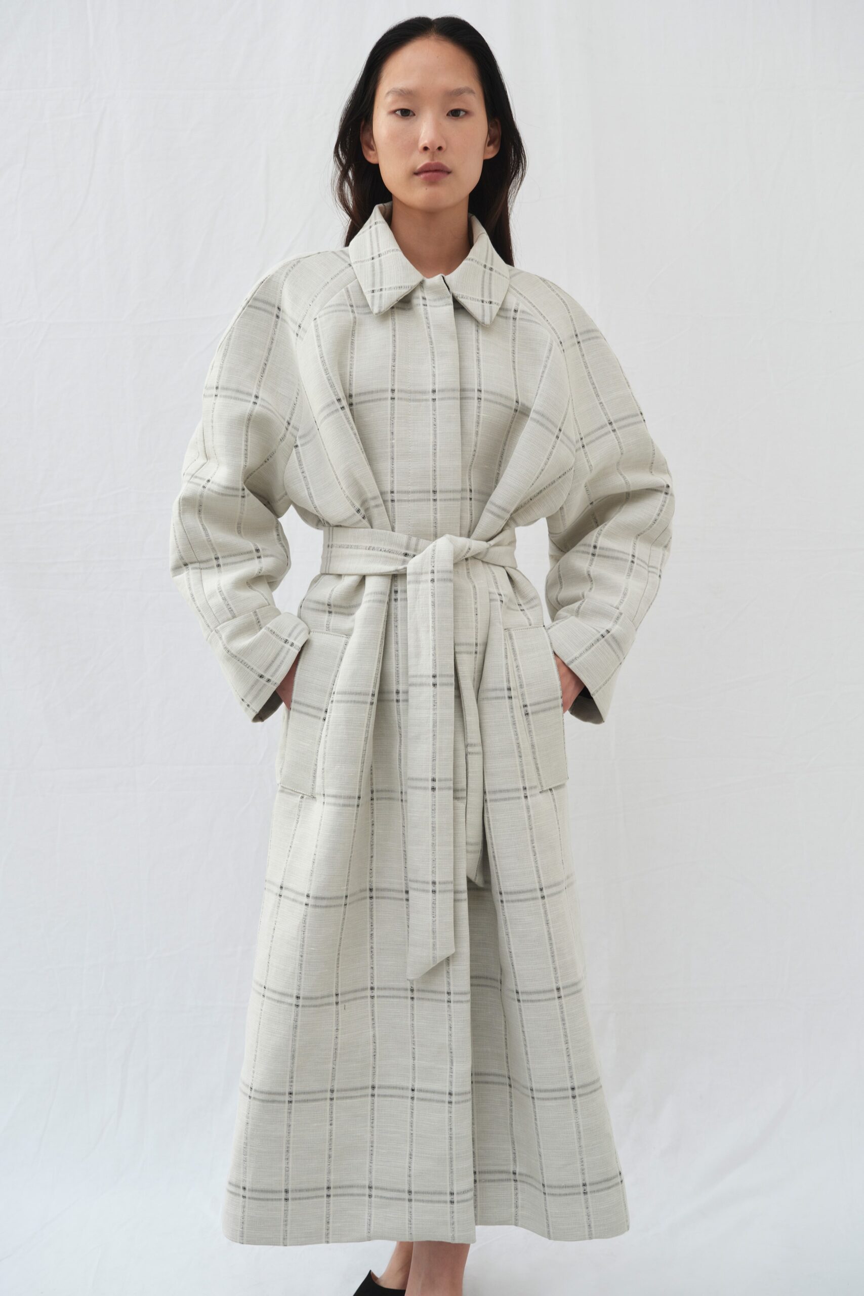 A relaxed beige checked coat with long sleeves and a belted waist.