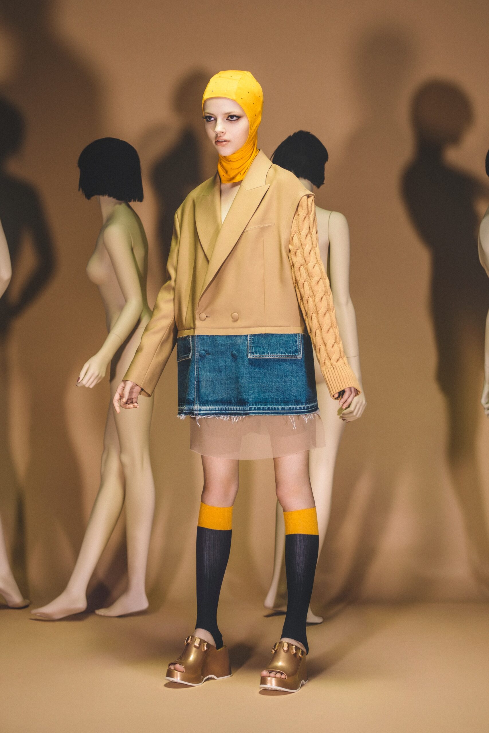 A relaxed beige jacket paired with a blue denim skirt featuring long sleeves and an asymmetric design.