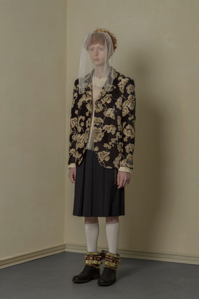 A fitted black floral blazer paired with a pleated skirt, showcasing a unique and stylish look.