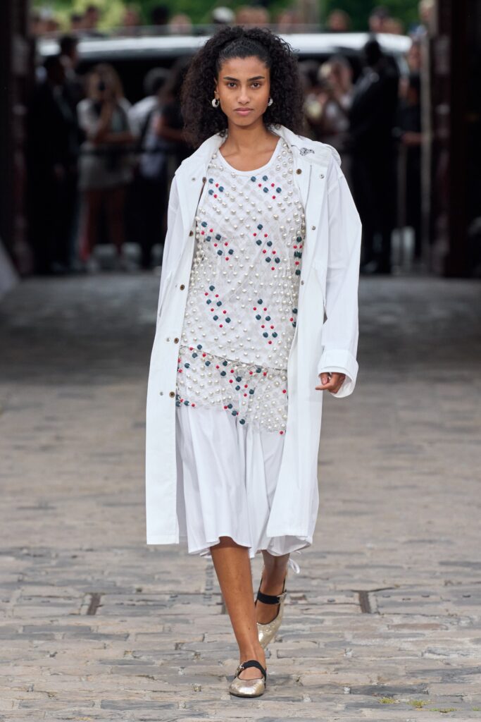 A relaxed white dress layered under a collared coat with short sleeves.