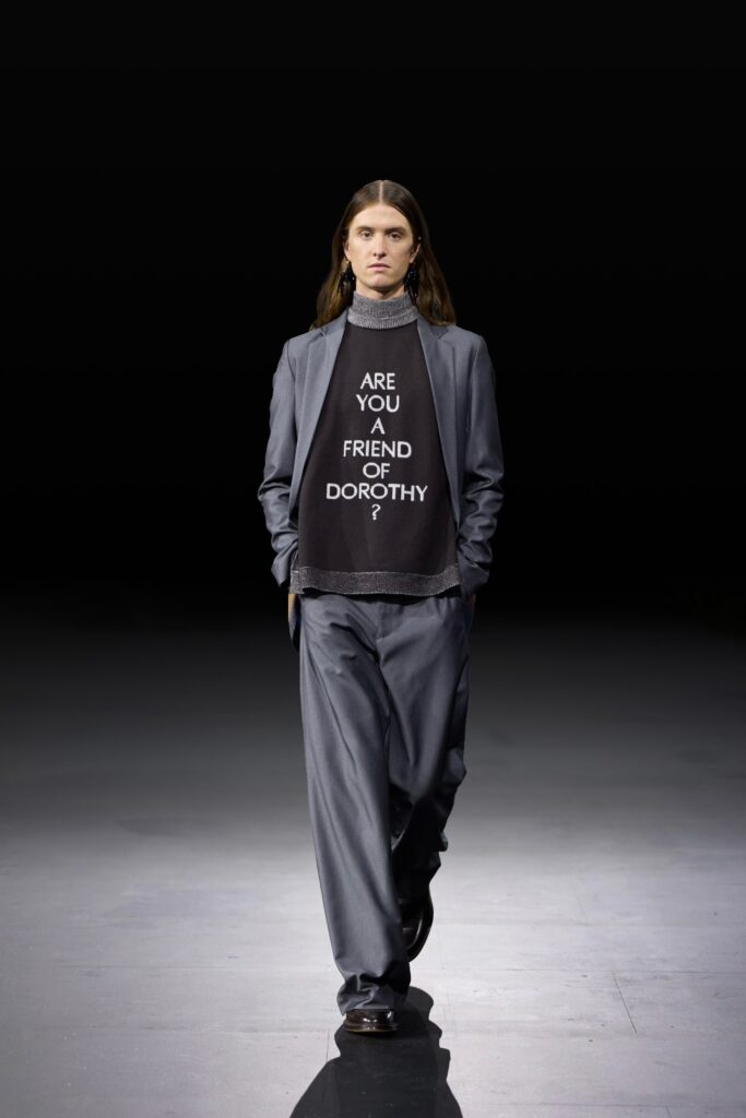 An oversized gray blazer paired with black pants and a graphic sweater underneath.
