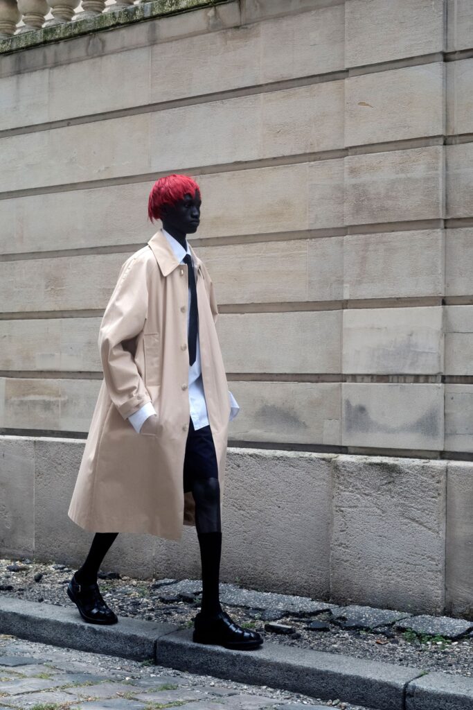 An oversized beige coat worn over a white collared shirt, creating a stylish layered look.