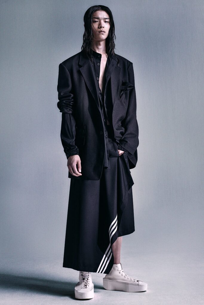 A relaxed black blazer with long sleeves and a collared design paired with an asymmetric skirt.