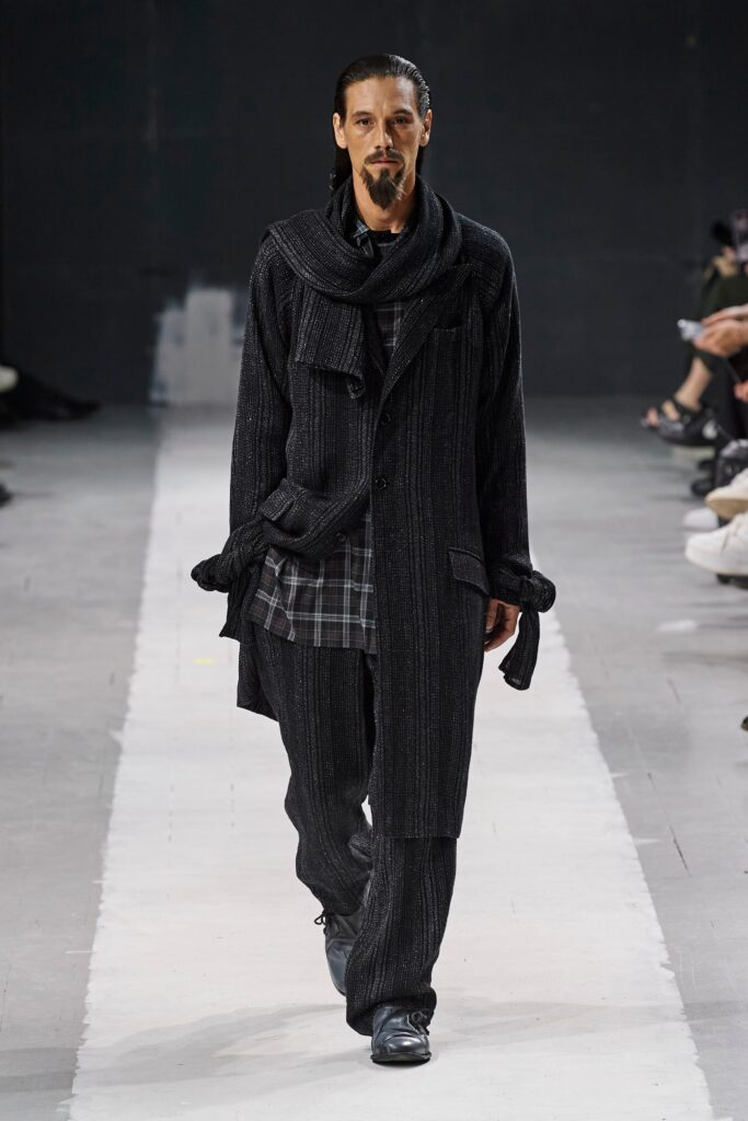 A relaxed black wool coat with long sleeves and a collared design, paired with matching pants.