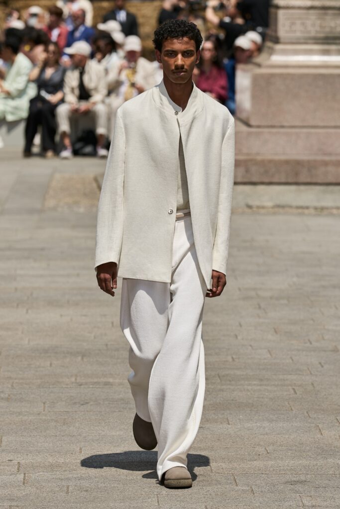 A relaxed white jacket with long sleeves and a collared design, paired with straight-leg pants.