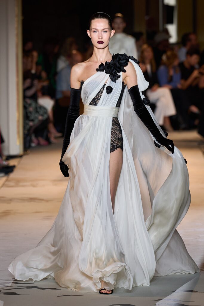A relaxed white silk sleeveless dress with a high neckline and asymmetric, tiered design.