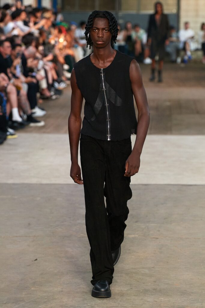 A fitted black sleeveless top with a zippered detail paired with straight-leg pants.