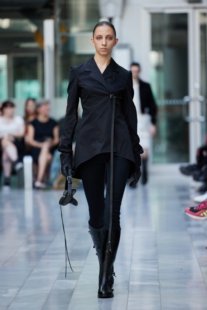 A fitted black asymmetric jacket paired with sleek black pants, creating a modern silhouette.