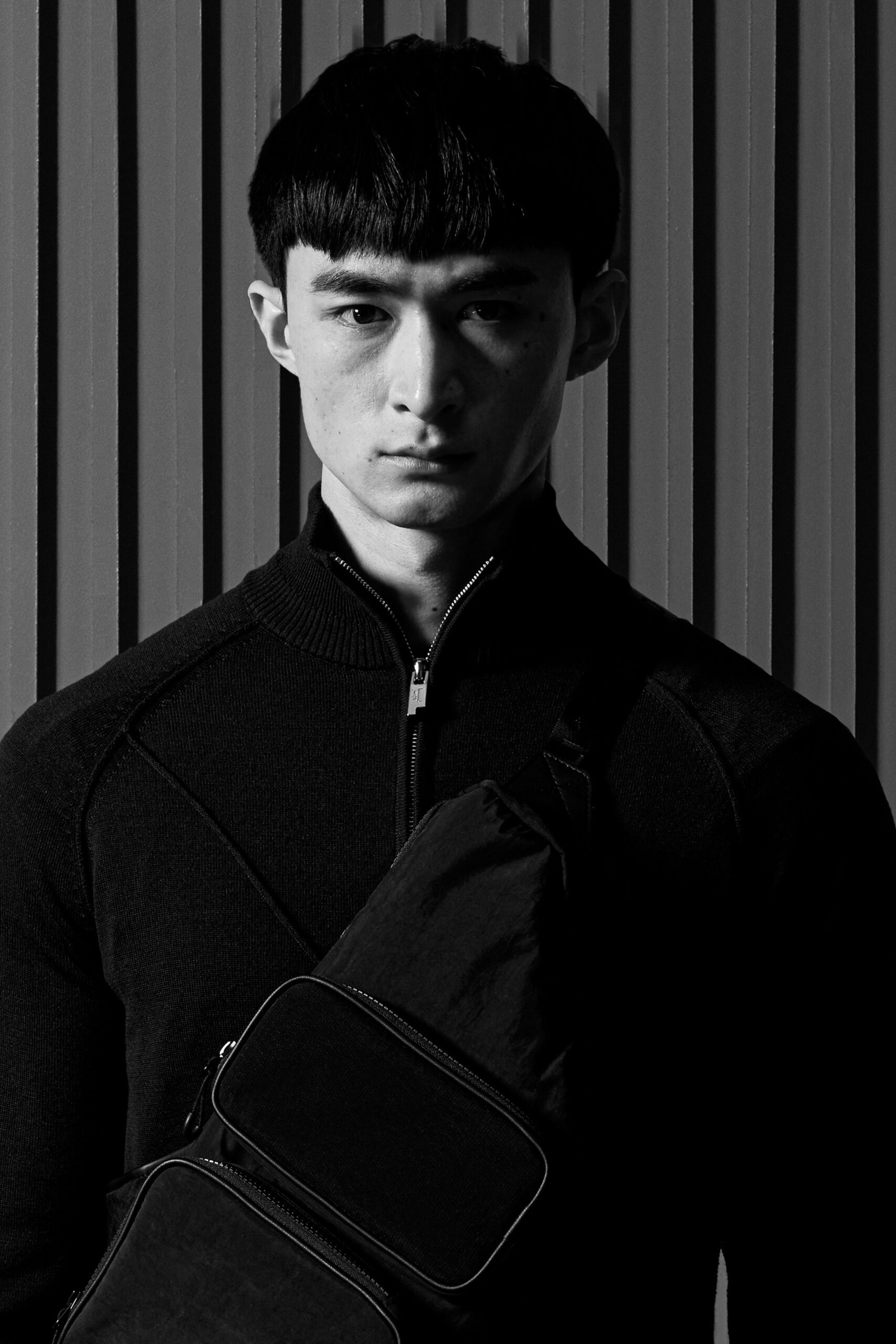 A fitted black cotton sweater with a high neckline and zippered detail.