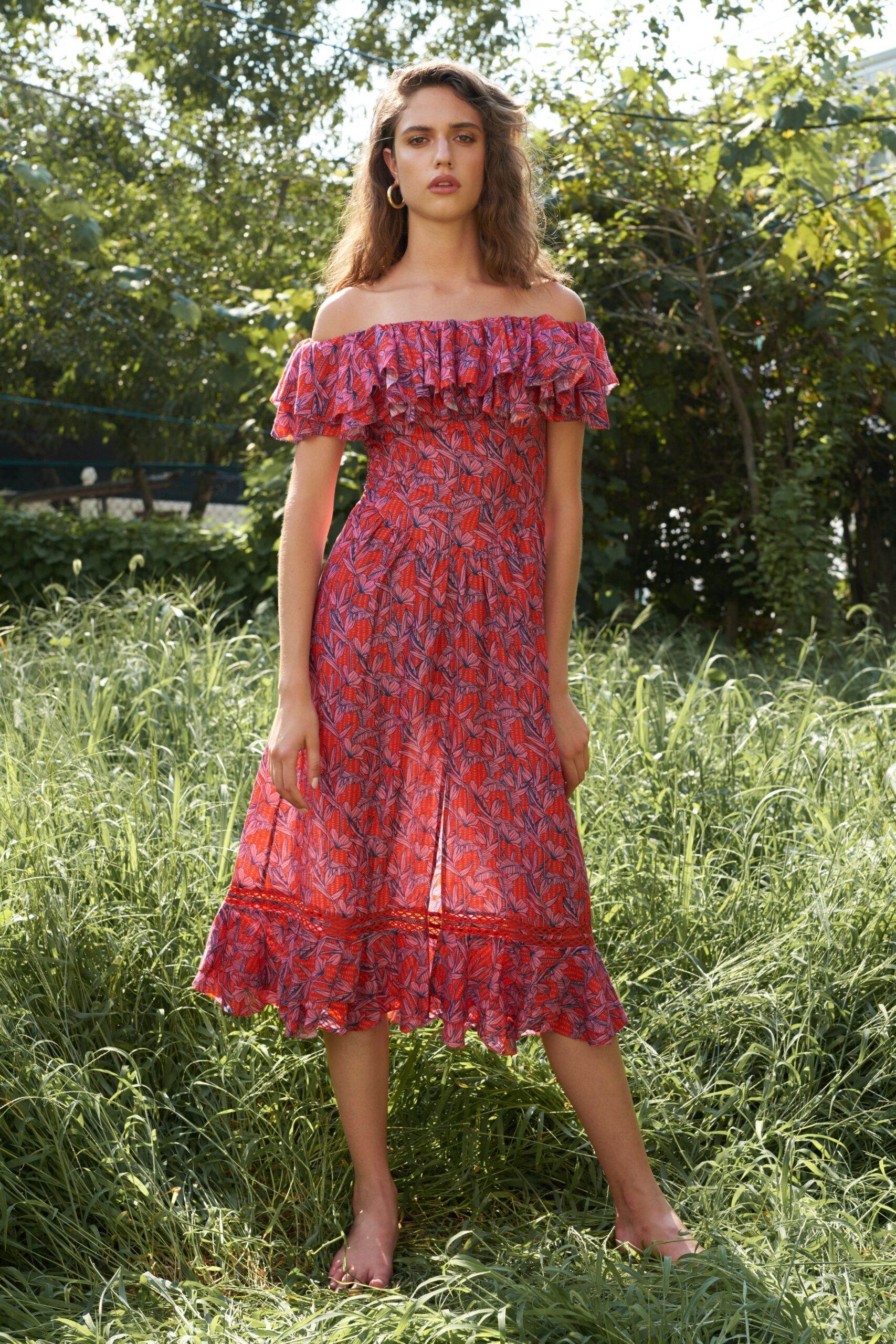 A relaxed red cotton off-shoulder dress with ruffled details and a tiered hemline.