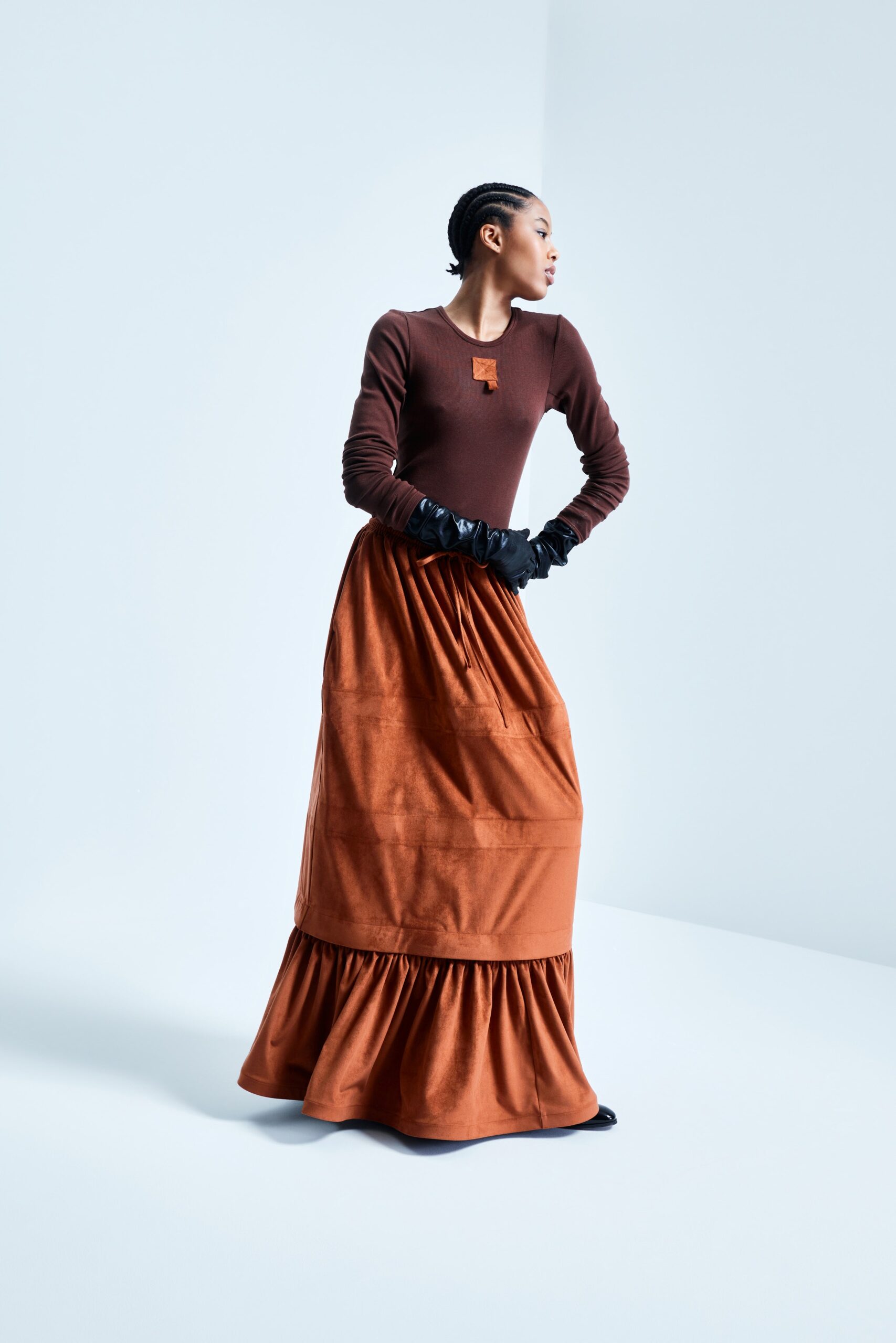 This relaxed long-sleeve dress in rich brown cotton features a tiered silhouette that adds volume and movement. The round neckline complements the flowing design, creating a harmonious balance between structure and fluidity.