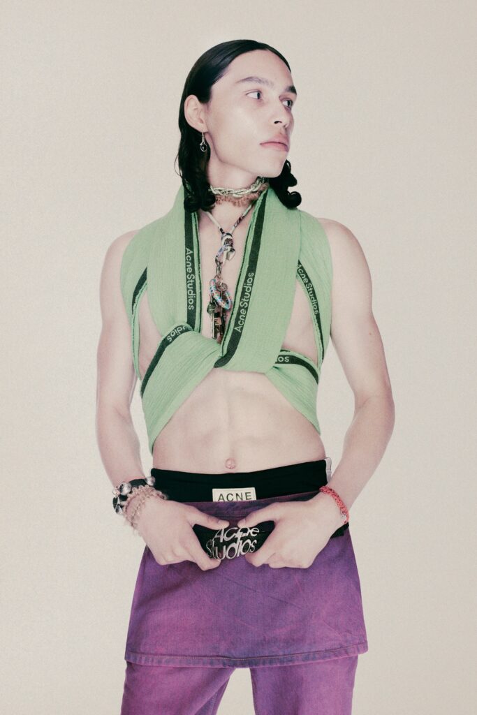 A fitted sleeveless green top with a high-neck and an asymmetric cropped purple skirt.