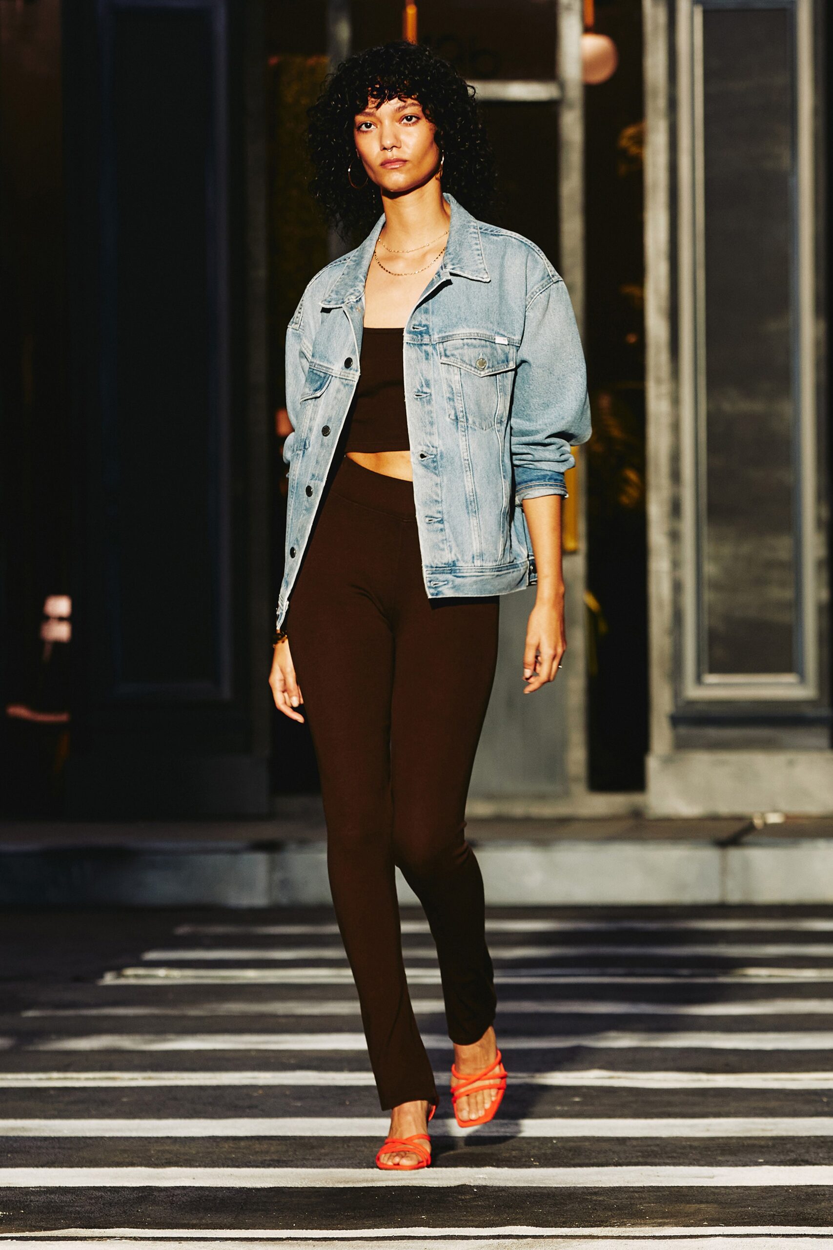 A fitted blue denim jacket paired with brown fitted pants, creating a stylish casual look.