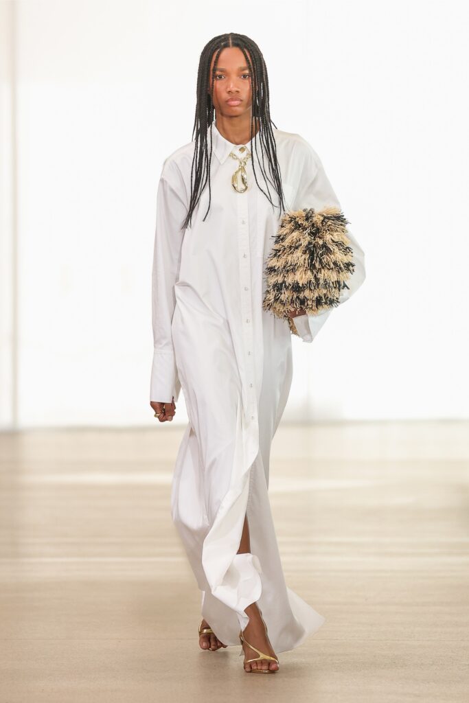 A relaxed white cotton shirt-dress with long sleeves and a buttoned tiered design.
