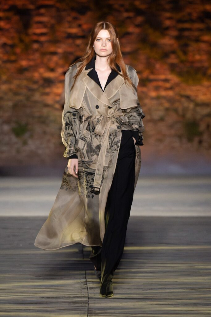 A relaxed beige silk trench coat paired with black pants, featuring a collared design and layered details.
