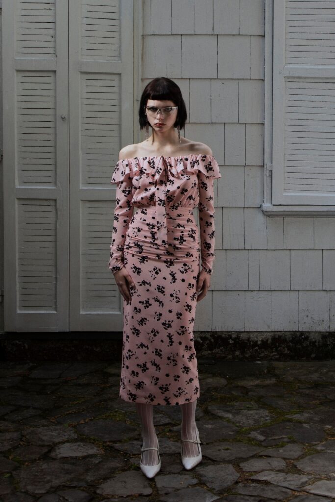 A fitted pink floral dress with long sleeves and ruffled details, perfect for a stylish look.