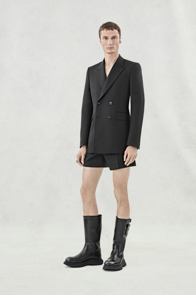 A fitted black blazer with a collared neckline paired with an asymmetric skirt.
