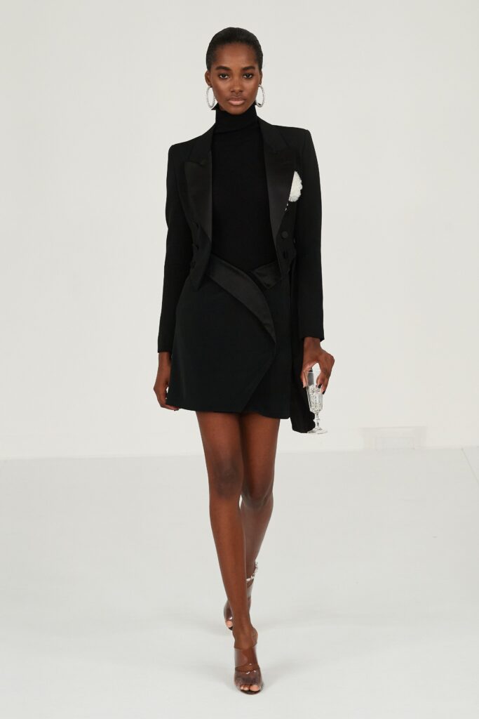 A fitted black silk dress with a long-sleeve jacket featuring an asymmetric design.