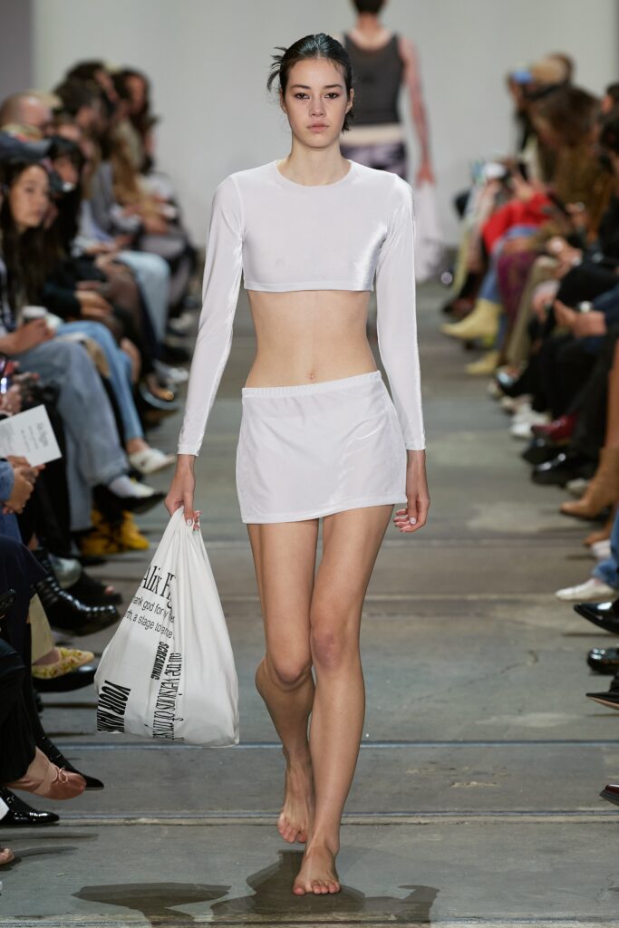 A fitted white silk long-sleeve top paired with a mini skirt, showcasing a modern silhouette.