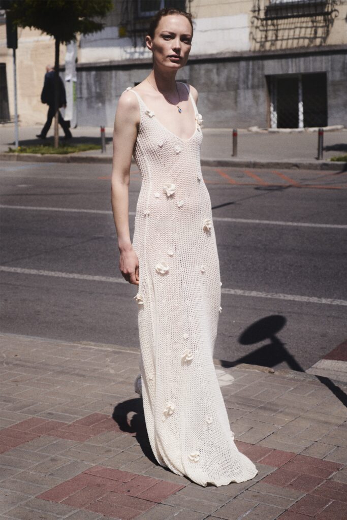 A fitted white cotton sleeveless dress with a V-neckline and tiered design details.