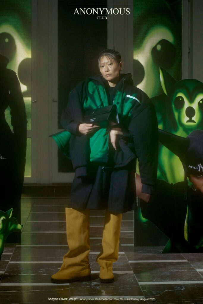 An oversized black coat layered over yellow pants, featuring a collared design and long sleeves.