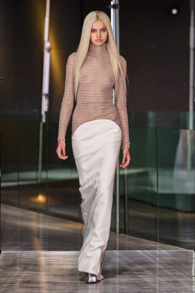 A fitted white silk dress with long sleeves and an asymmetric design detail.