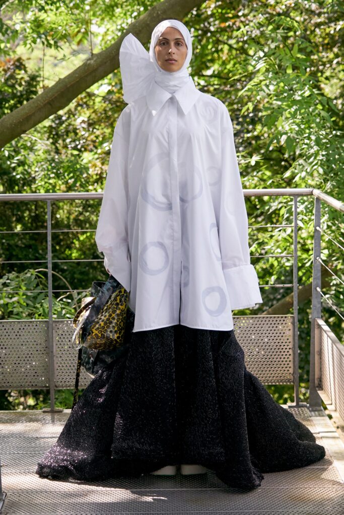 A relaxed black and white dress with long sleeves, a collared neckline, and an asymmetric layered design.