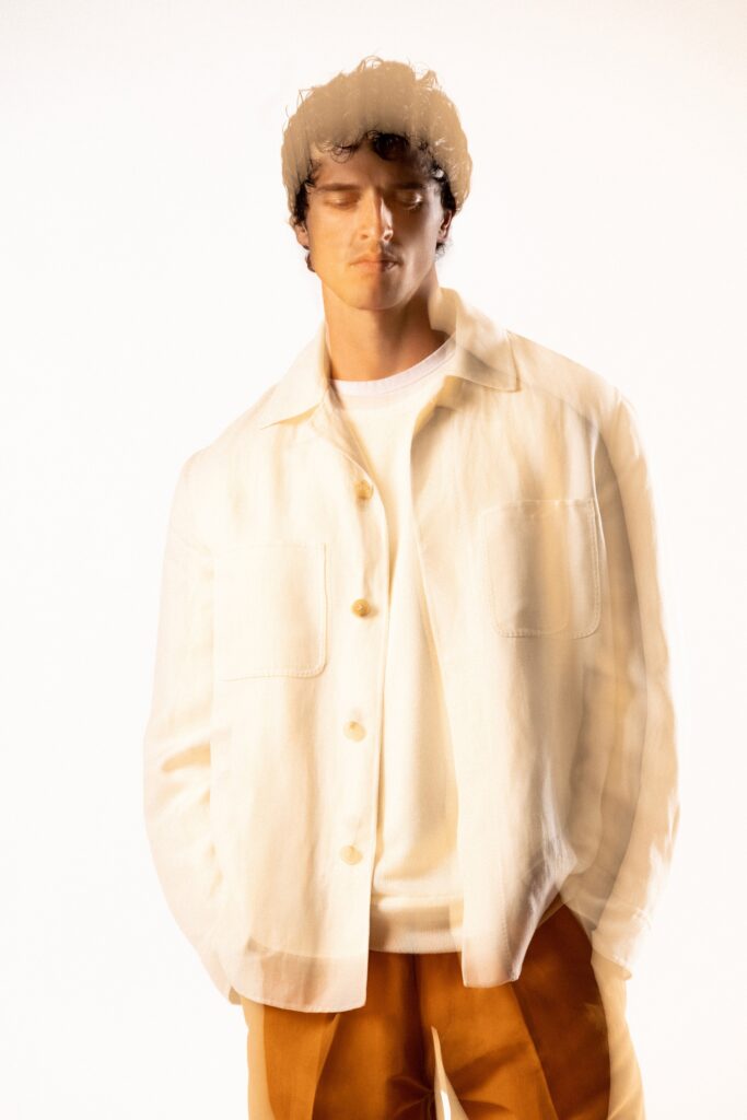 A relaxed white cotton jacket paired with brown pants, featuring a collared design and buttoned details.