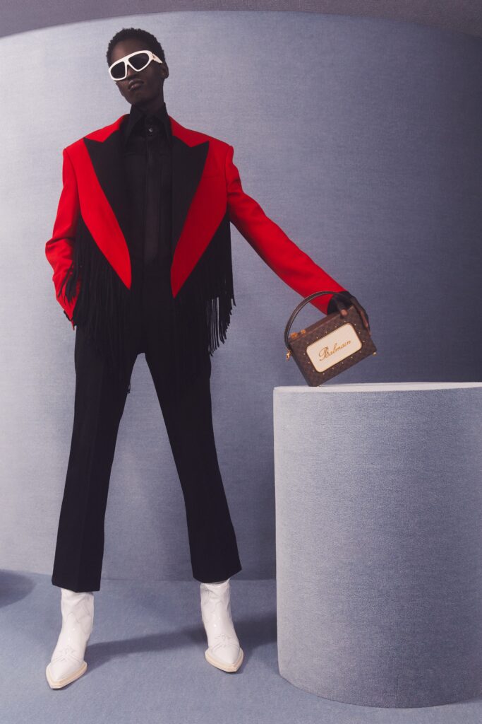 A tailored red jacket with fringes paired with black pants for a striking runway look.