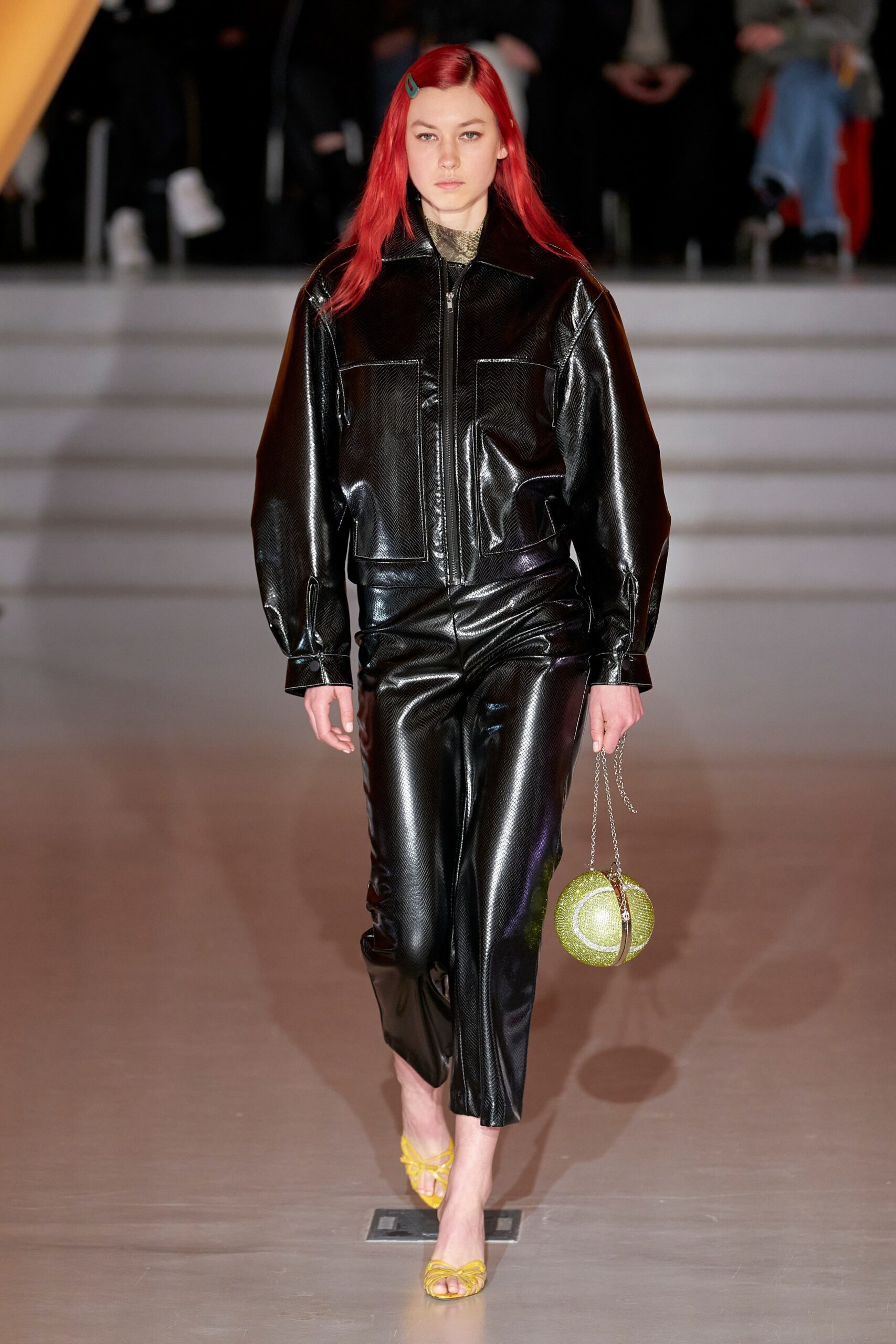 A fitted black leather jacket with long sleeves and a collared design paired with matching pants.