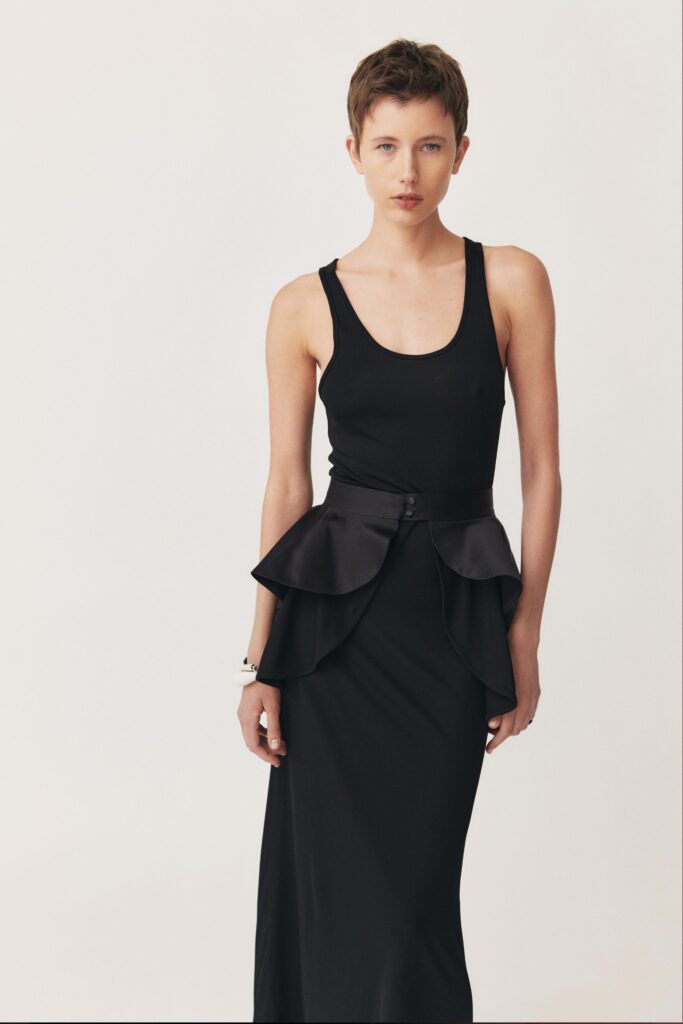 A fitted black sleeveless dress with a high neckline and layered design details.