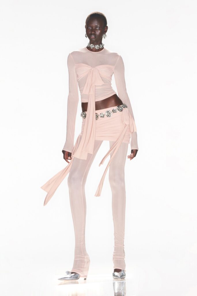 A fitted pink silk long-sleeve top with asymmetric layered details paired with matching pants.