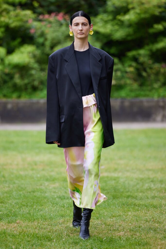 An oversized black blazer paired with a high-waisted skirt featuring a pink and green floral print.