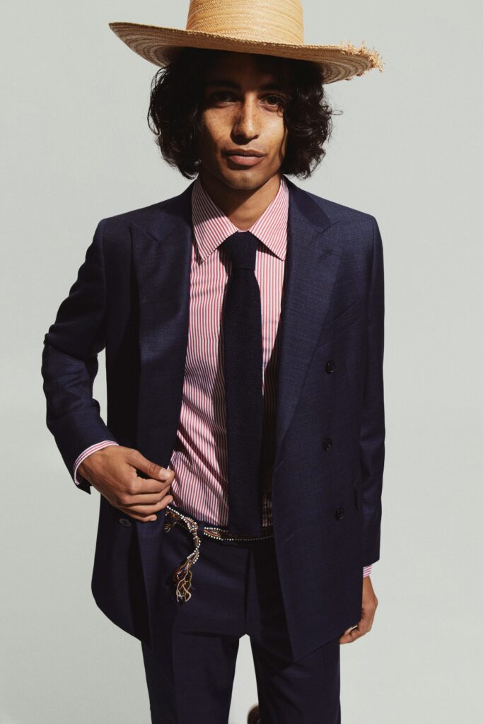 A tailored navy suit with a striped shirt and long sleeves, featuring a double-breasted design.