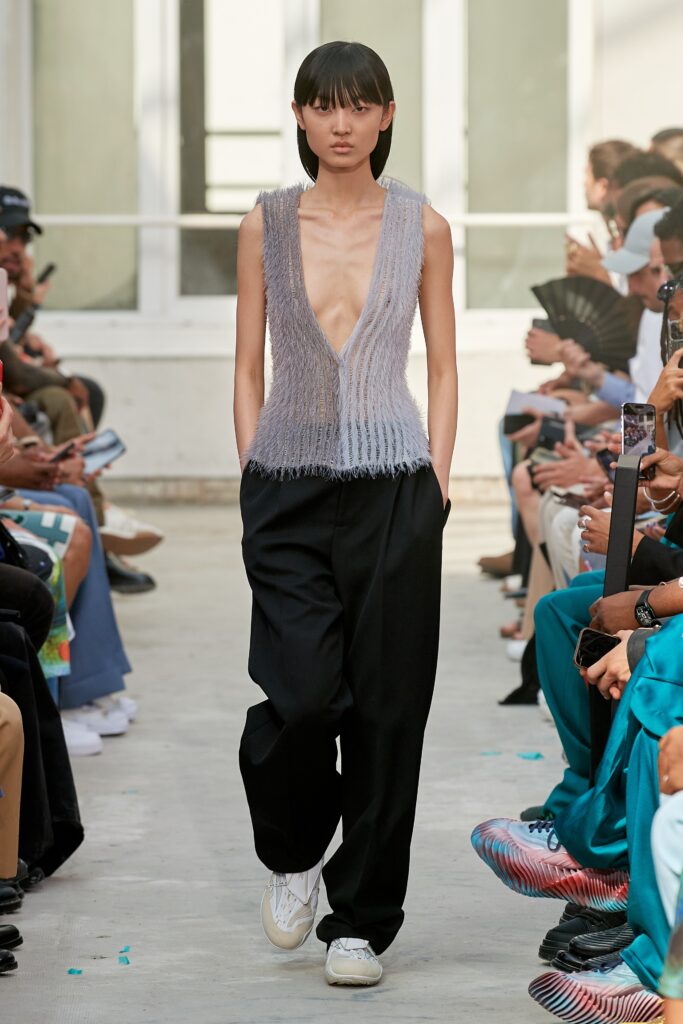 A relaxed gray silk sleeveless top paired with black pants featuring an asymmetric design.