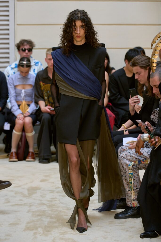 A fitted black silk dress with a sleeveless design and asymmetric detailing.