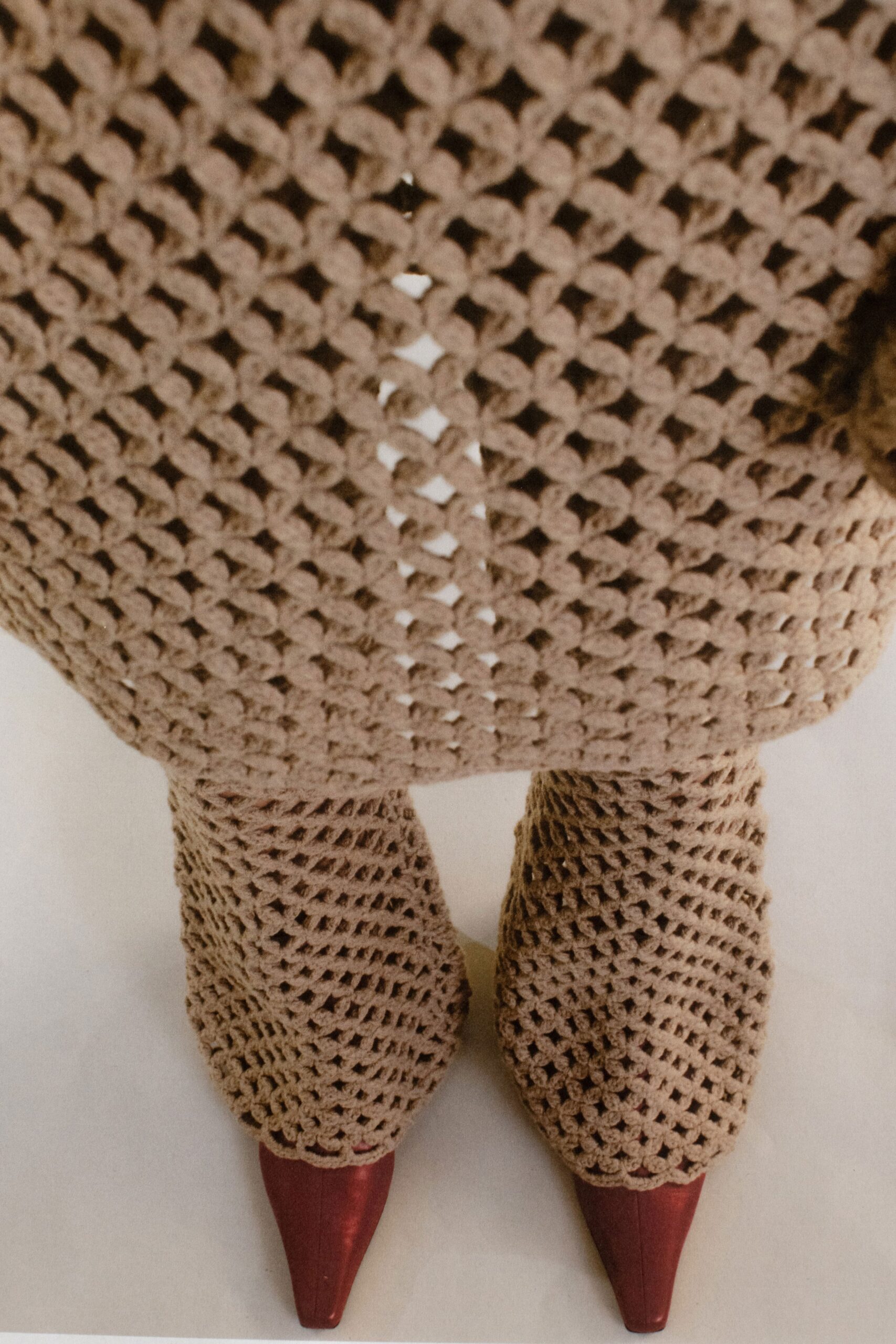 A fitted beige knit long-sleeve dress with an asymmetric design detail.