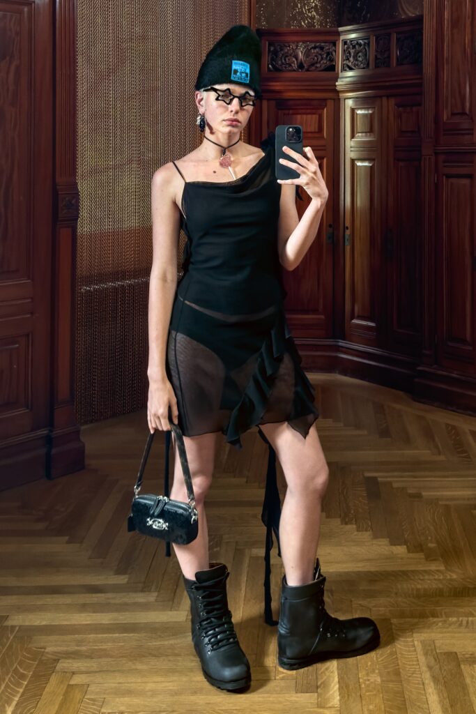 A fitted black sheer dress with an asymmetric design and ruffled details.