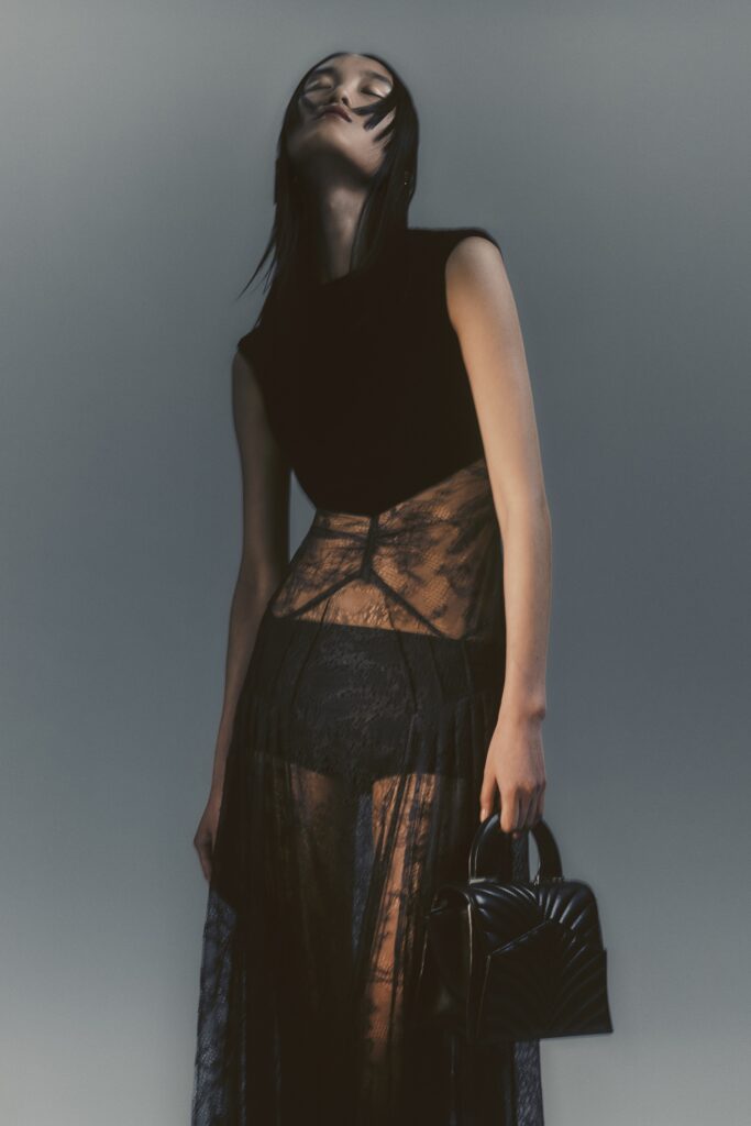 A fitted black lace dress with a sleeveless design and layered sheer details.
