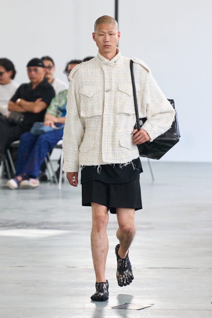 An oversized white collared jacket with long sleeves paired with a black asymmetric skirt.