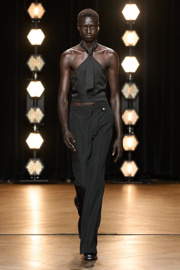 A fitted black silk sleeveless top with a high-neck and straight-leg pants.