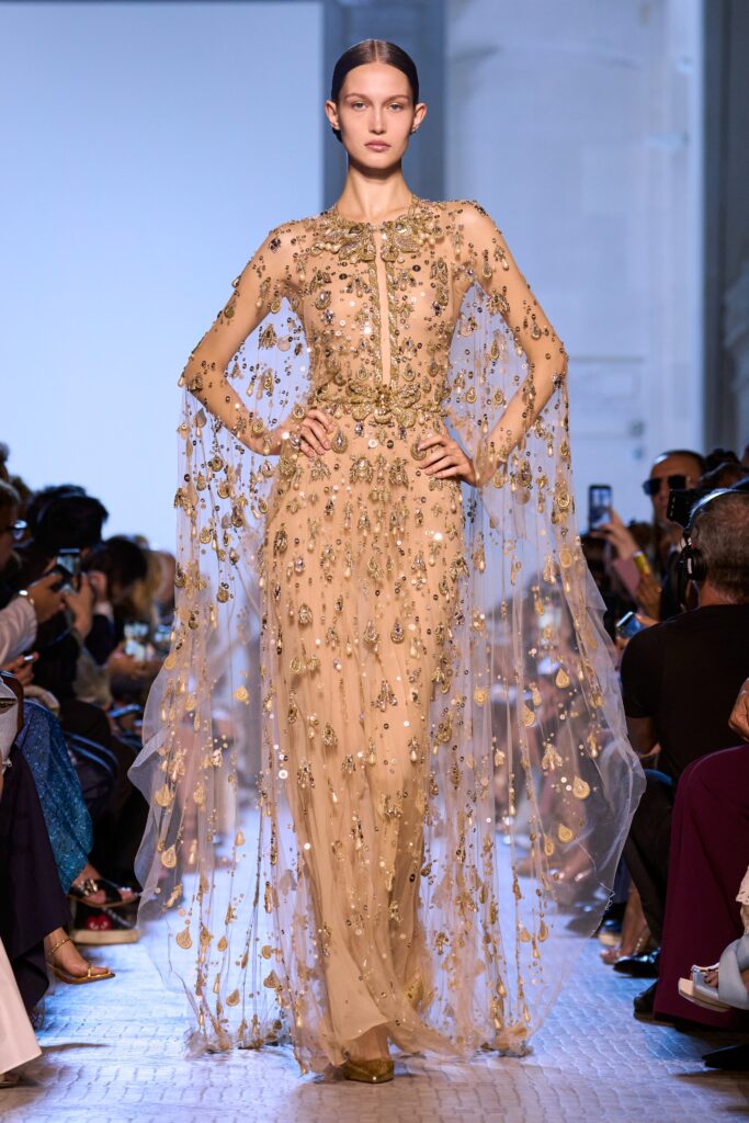 A fitted beige silk gown with long sleeves, high neckline, and intricate embroidery.