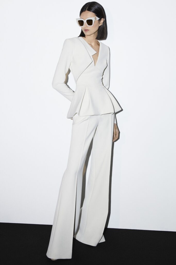 A fitted white suit with a V-neckline, long sleeves, and flared pants.