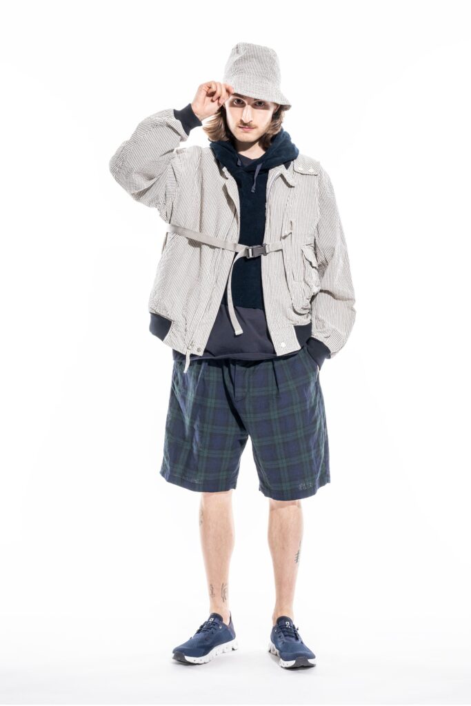A relaxed gray checked jacket paired with blue shorts and a hooded sweatshirt.