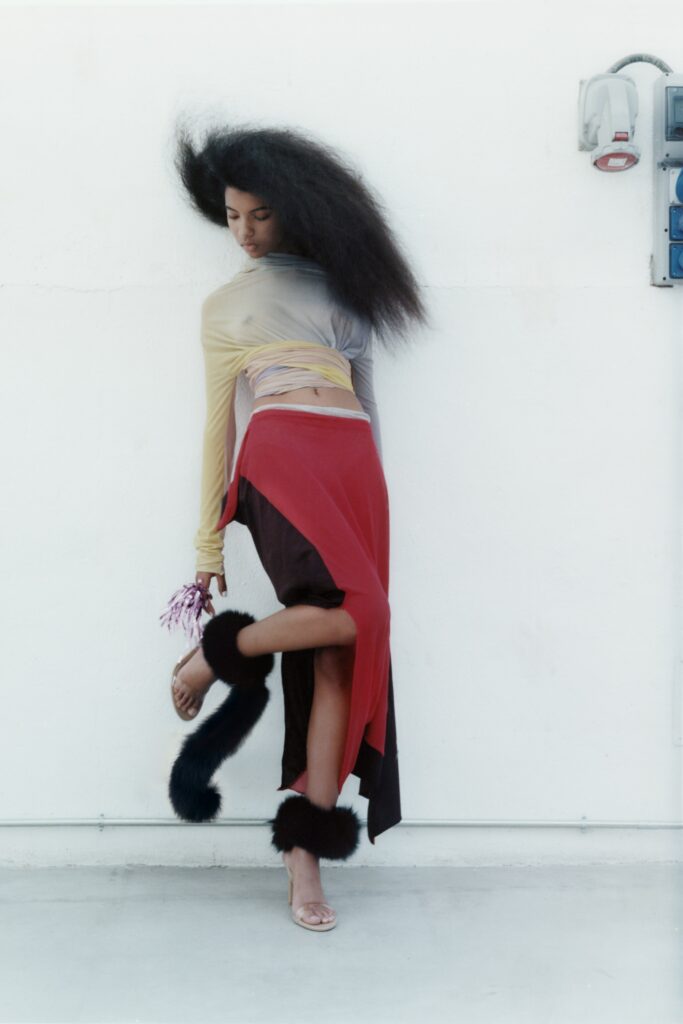 A relaxed fit asymmetric red silk skirt paired with a long-sleeve crop top.